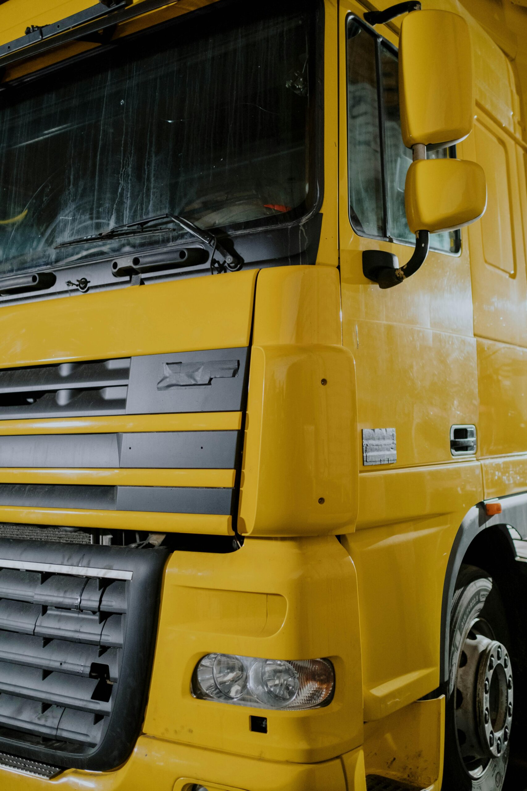 Detailed close-up of a yellow truck parked indoors, showcasing its design and structure.